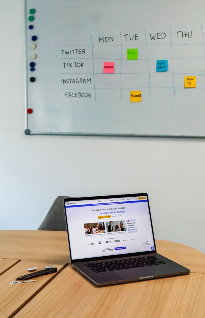 services-01 A modern office setup featuring a laptop and a whiteboard schedule for social media platforms.
